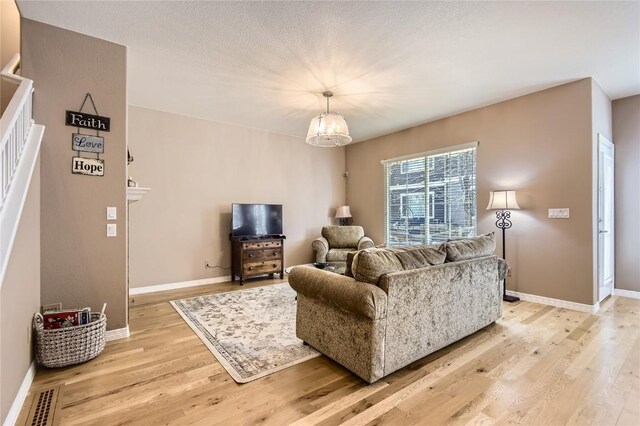 living room with light wood-style floors, baseboards, and a chandelier