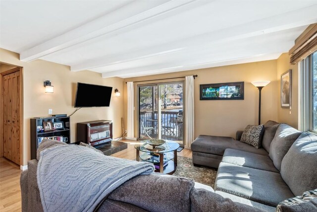 living area with light wood finished floors and beam ceiling