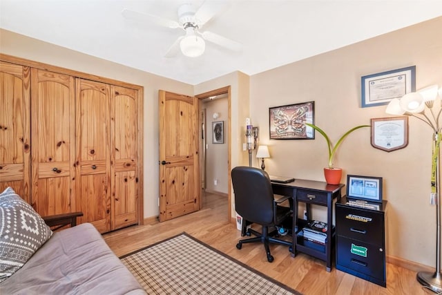 office area featuring baseboards, a ceiling fan, and light wood-style flooring