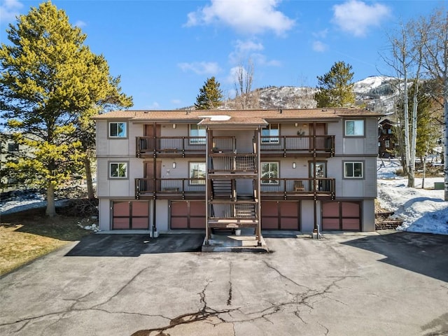 view of property featuring an attached garage, driveway, and a mountain view