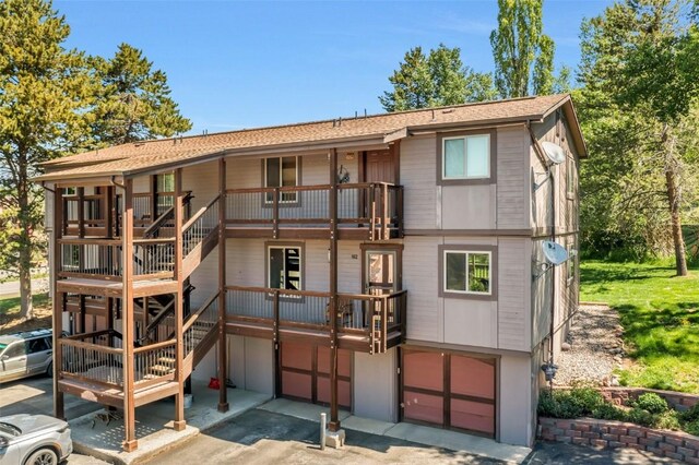 2930 Columbine Dr Unit 102, Steamboat Springs, CO 80487 - rear view of property with a garage, a balcony, stairs, asphalt driveway, and a shingled roof