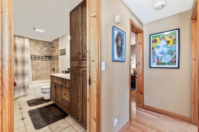 bathroom with tile patterned floors, shower / bath combo, toilet, baseboards, and vanity