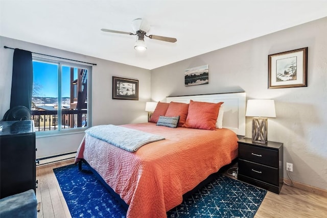 bedroom with baseboard heating, ceiling fan, baseboards, and wood finished floors
