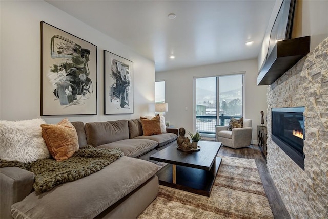 living area featuring a stone fireplace, wood finished floors, and recessed lighting