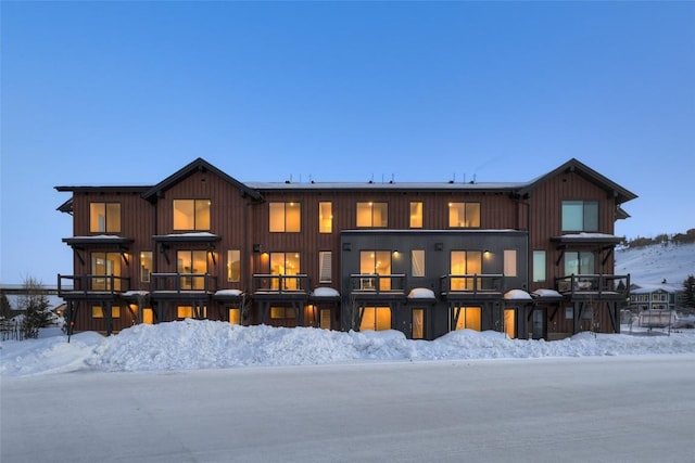 snow covered back of property with a balcony