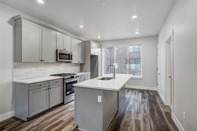 kitchen featuring a sink, gray cabinets, dark wood finished floors, baseboards, and appliances with stainless steel finishes