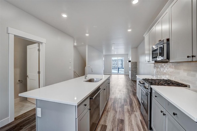 kitchen with a sink, decorative backsplash, stainless steel appliances, light countertops, and dark wood-type flooring