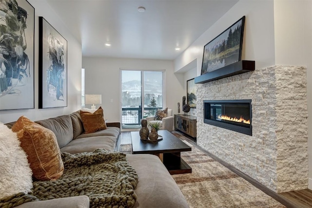 living area featuring wood finished floors, a stone fireplace, and recessed lighting