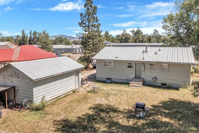 back of house featuring a mountain view and a lawn