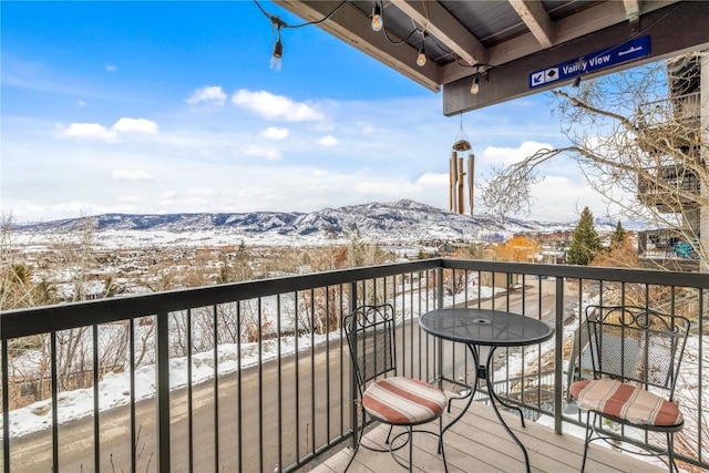 snow covered back of property featuring a mountain view