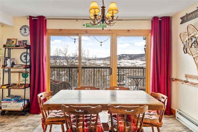 dining room featuring a baseboard radiator, plenty of natural light, a notable chandelier, and a mountain view