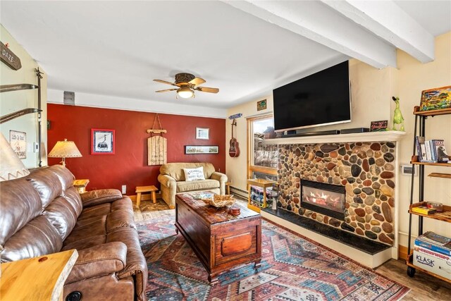 2626 Longthong Rd Unit 104, Steamboat Springs, CO 80487 - living area featuring a ceiling fan, a stone fireplace, beamed ceiling, a baseboard heating unit, and wood finished floors