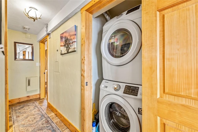 laundry room featuring baseboards, stacked washing maching and dryer, laundry area, and light wood-style floors