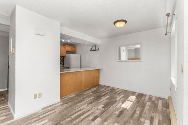20 Sequoia Ct Unit 20, Steamboat Springs, CO 80487 - kitchen featuring freestanding refrigerator, brown cabinetry, wood finished floors, baseboards, and a textured ceiling