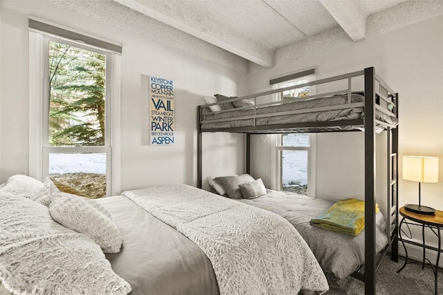 bedroom with beamed ceiling, carpet floors, and a textured ceiling