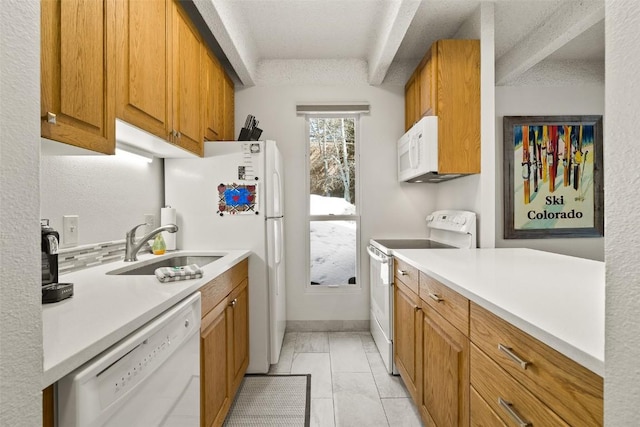 kitchen featuring brown cabinetry, white appliances, and a sink