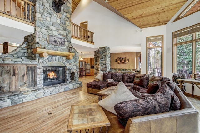 living room featuring a fireplace, high vaulted ceiling, decorative columns, wooden ceiling, and wood finished floors