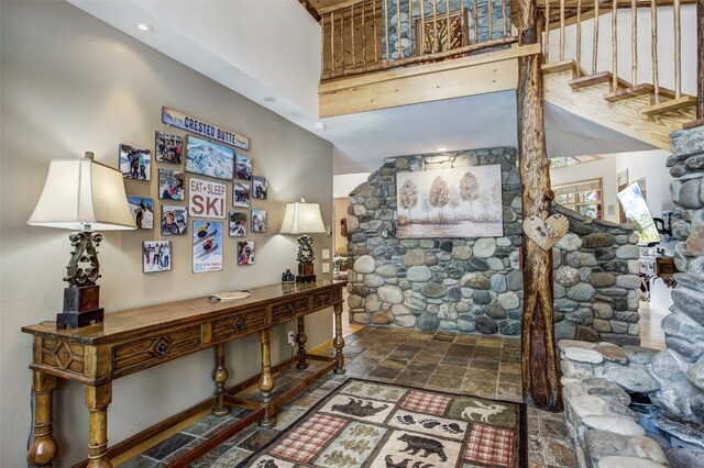 entrance foyer with baseboards, stone finish flooring, and stairway