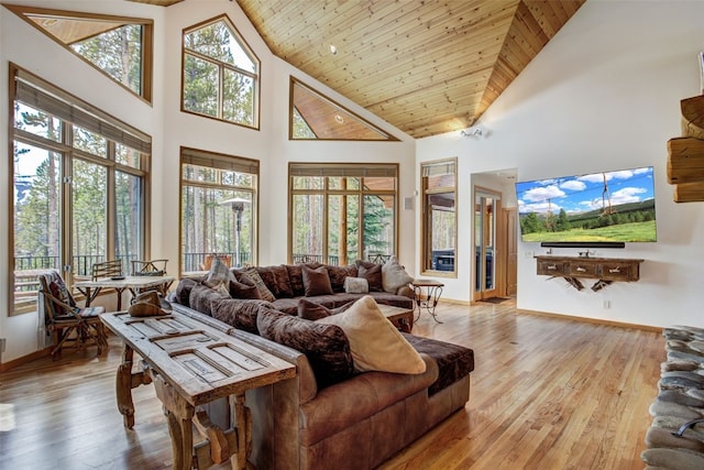 living area featuring baseboards, light wood finished floors, and high vaulted ceiling