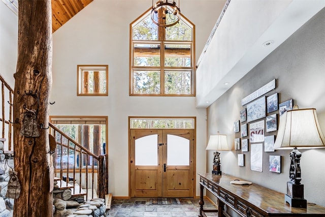 entrance foyer featuring stone tile flooring, stairs, baseboards, high vaulted ceiling, and wood ceiling