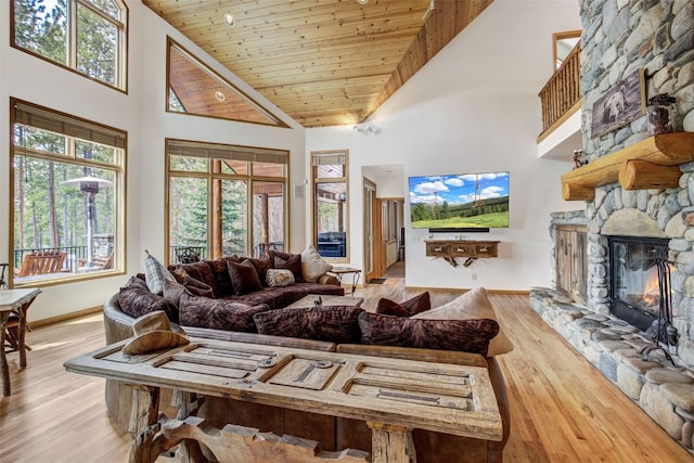 living area featuring plenty of natural light, a high ceiling, a fireplace, and wood finished floors