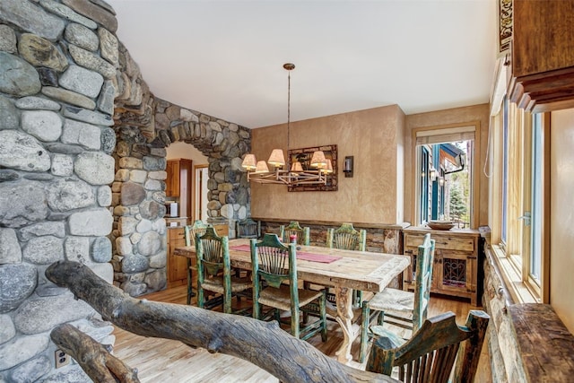 dining area with arched walkways, wood finished floors, and a chandelier