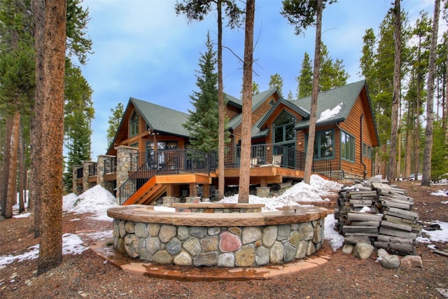 snow covered house featuring stairway and a deck