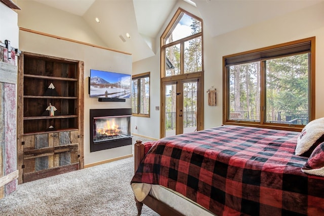 bedroom with access to outside, a glass covered fireplace, carpet, baseboards, and vaulted ceiling