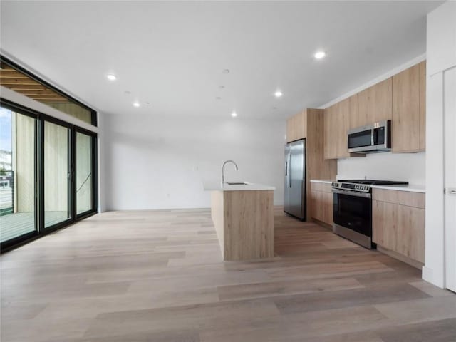 740 Blue River Pkwy Unit A21, Silverthorne, CO 80498 - kitchen featuring light brown cabinetry, stainless steel appliances, a sink, modern cabinets, and a kitchen island with sink
