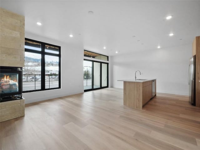 740 Blue River Pkwy Unit A21, Silverthorne, CO 80498 - kitchen featuring a sink, an island with sink, open floor plan, stainless steel appliances, and light wood finished floors