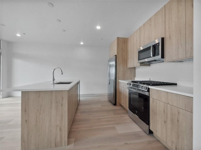 740 Blue River Pkwy Unit A21, Silverthorne, CO 80498 - kitchen with light brown cabinetry, a sink, light wood-type flooring, modern cabinets, and appliances with stainless steel finishes