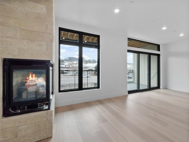 740 Blue River Pkwy Unit A21, Silverthorne, CO 80498 - unfurnished living room featuring a tile fireplace, wood finished floors, recessed lighting, and a mountain view