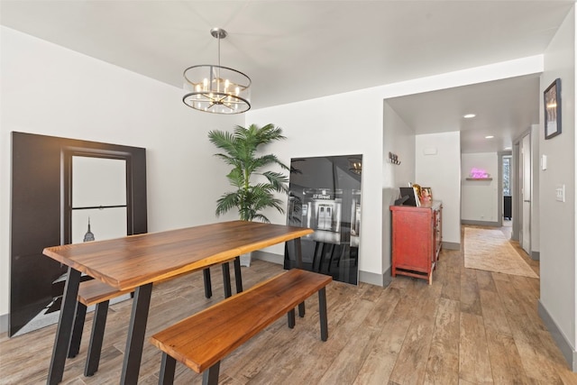 dining space with a chandelier, light wood-style floors, and baseboards