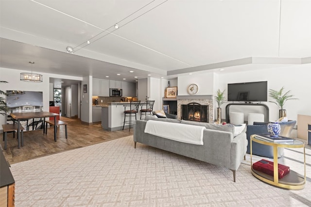 living room featuring a chandelier, a warm lit fireplace, and light wood-type flooring