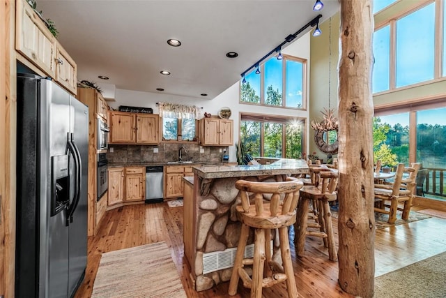 1996 Al Gulch Rd, Jefferson, CO 80456 - kitchen featuring refrigerator with ice dispenser, light wood finished floors, a breakfast bar, backsplash, and recessed lighting