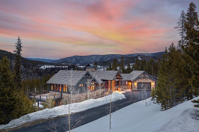 exterior space featuring driveway, a forest view, an attached garage, and a mountain view