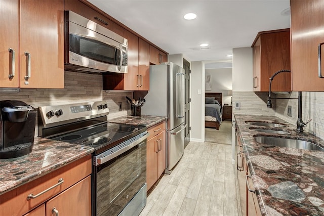 9359 State Highway 9 Unit G5, Breckenridge, CO 80424 - kitchen featuring stainless steel appliances, a sink, light wood-style flooring, backsplash, and dark stone countertops