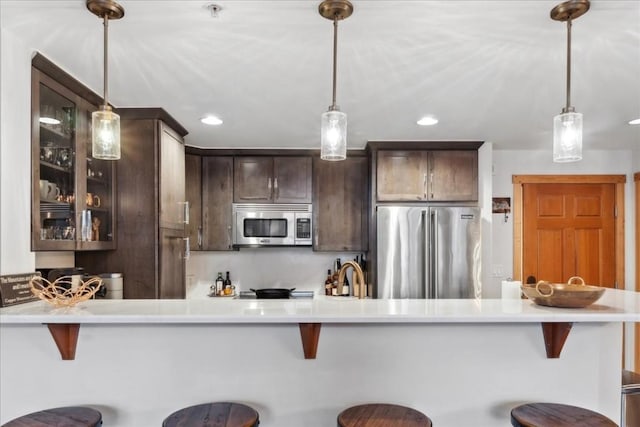 910 Copper Rd Unit 105, Frisco, CO 80443 - kitchen featuring appliances with stainless steel finishes, dark brown cabinetry, glass insert cabinets, a kitchen breakfast bar, and recessed lighting
