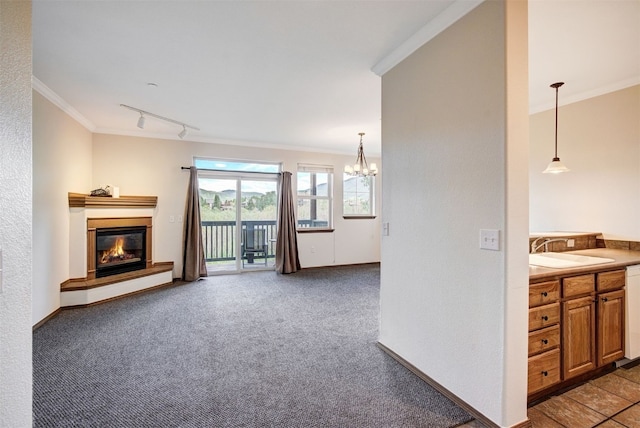 951 N Ten Mile Dr Unit C15, Frisco, CO 80443 - unfurnished living room featuring ornamental molding, a glass covered fireplace, a chandelier, carpet, and track lighting
