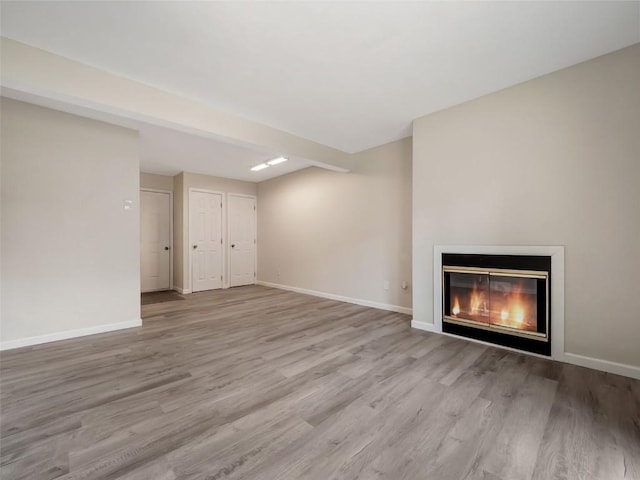 1565 Shadow Run Frontage Unit 104, Steamboat Springs, CO 80487 - unfurnished living room with wood finished floors, a glass covered fireplace, and baseboards
