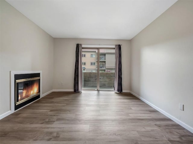 1565 Shadow Run Frontage Unit 104, Steamboat Springs, CO 80487 - unfurnished living room featuring a glass covered fireplace, wood finished floors, and baseboards