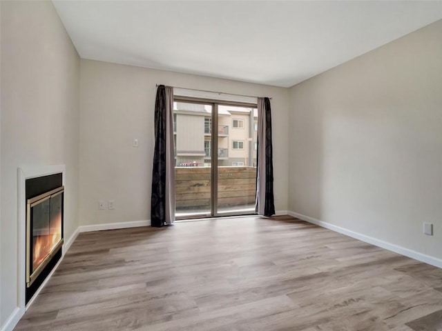 1565 Shadow Run Frontage Unit 104, Steamboat Springs, CO 80487 - unfurnished living room with wood finished floors, a glass covered fireplace, and baseboards