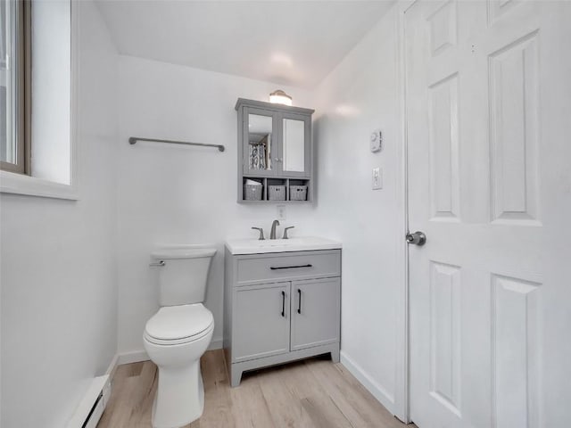 1565 Shadow Run Frontage Unit 104, Steamboat Springs, CO 80487 - bathroom featuring vanity, wood finished floors, toilet, a baseboard radiator, and baseboards