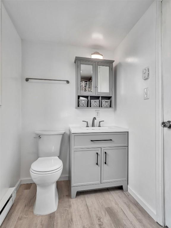 1565 Shadow Run Frontage Unit 104, Steamboat Springs, CO 80487 - bathroom with a baseboard heating unit, vanity, baseboards, wood finished floors, and toilet