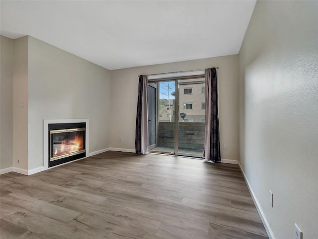 1565 Shadow Run Frontage Unit 104, Steamboat Springs, CO 80487 - unfurnished living room featuring a glass covered fireplace, wood finished floors, and baseboards