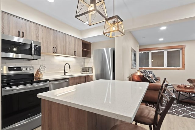 kitchen with open shelves, a sink, a breakfast bar area, stainless steel appliances, and a notable chandelier