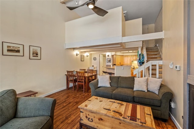 living room with dark hardwood / wood-style flooring, ceiling fan, and a high ceiling