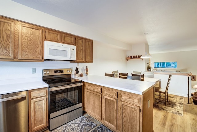 300 Primrose Path Unit 37, Breckenridge, CO 80424 - kitchen with stainless steel appliances, a peninsula, light countertops, light wood-type flooring, and hanging light fixtures