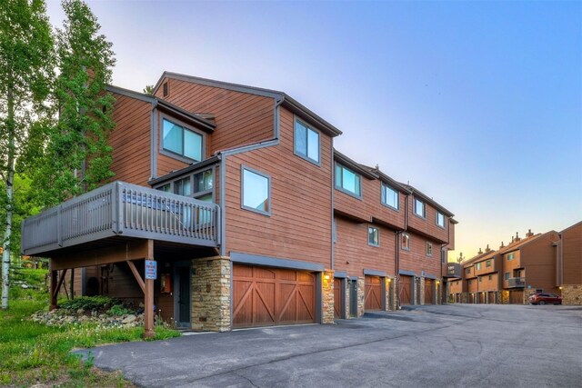 300 Primrose Path Unit 37, Breckenridge, CO 80424 - back of property at dusk with a garage, a deck, stone siding, and driveway