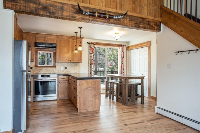 602 Ryan Gulch Rd Unit B, Silverthorne, CO 80498 - kitchen featuring a baseboard radiator, stove, freestanding refrigerator, a peninsula, and light wood-style floors
